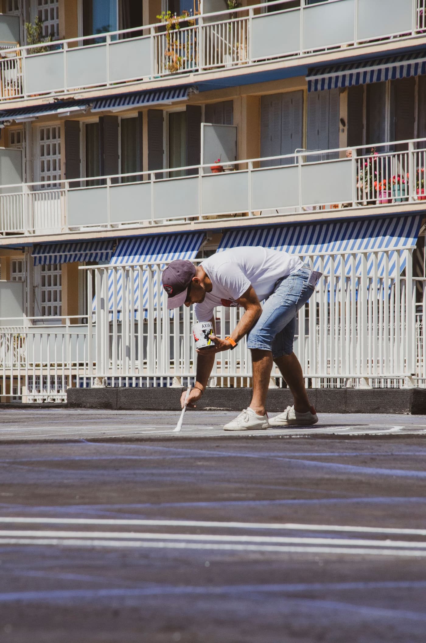 Line marker hand-finishing a white car park line with a brush and paint tin